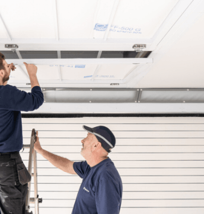 Two men installing an air filter inside a spray booth to keep it clean - Installing Air Filters