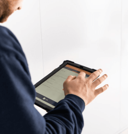 Man on handheld tablet ticking off tasks for Legionella Testing in Schools