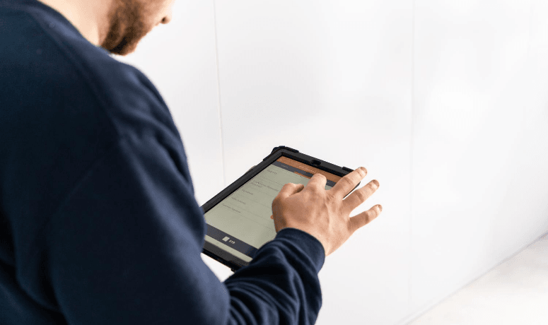 Man on handheld tablet ticking off tasks for Legionella Testing in Schools