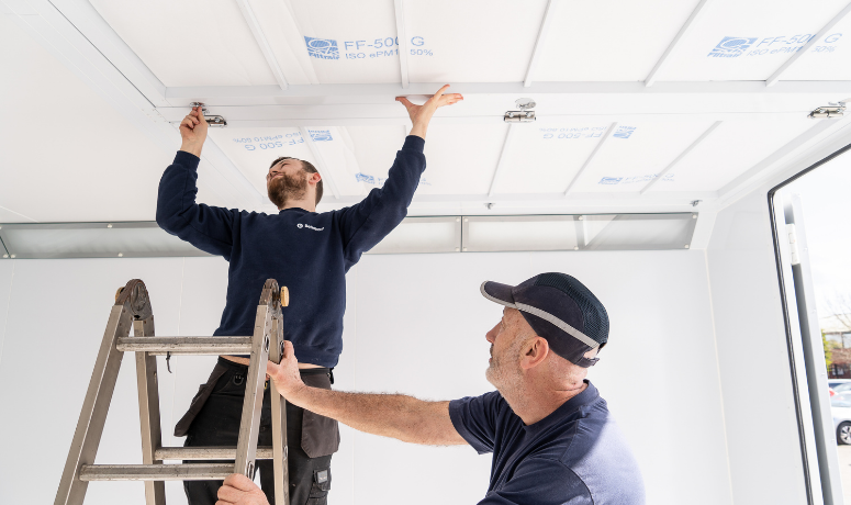 Two men changing spray booth filters