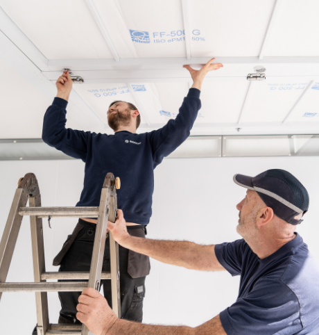 Two men changing spray booth filters